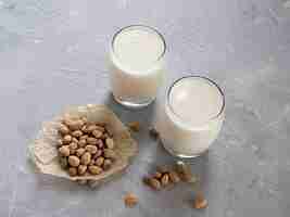 Photo lait de pistache dans une tasse en verre et pistaches sur fond de béton gris.