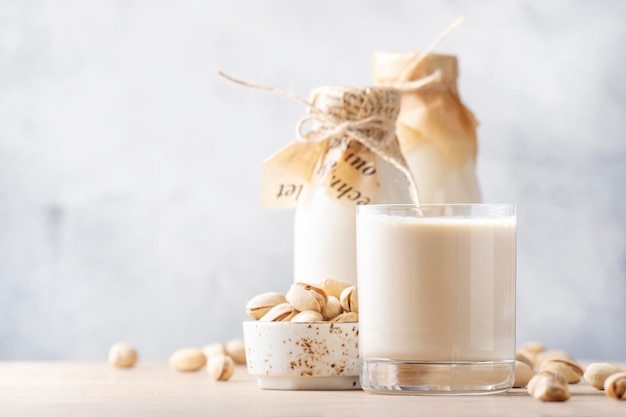 Lait de pistache végétalien en bouteilles agrandi fond de table beige Lait alternatif non laitier Nourriture et boisson végétariennes saines Concept de copie espace