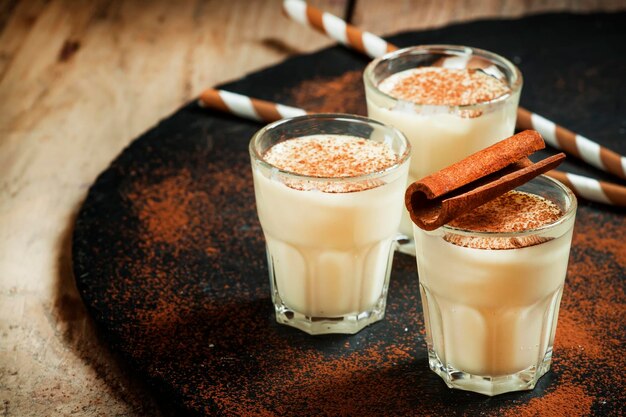 Photo lait de poule d'hiver traditionnel avec rhum au lait et saupoudrer de cannelle avec mise au point sélective de noix de muscade râpée