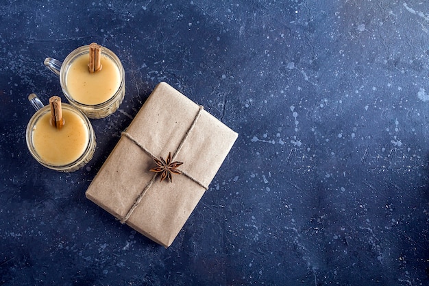 Lait de poule de Noël dans des verres avec cadeau et cannelle