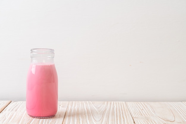 lait rose ou lait de fraise en bouteille sur bois