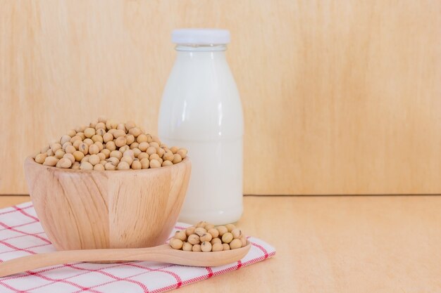 Lait de soja en bouteille de verre avec des fèves de soja à la cuillère sur fond en bois