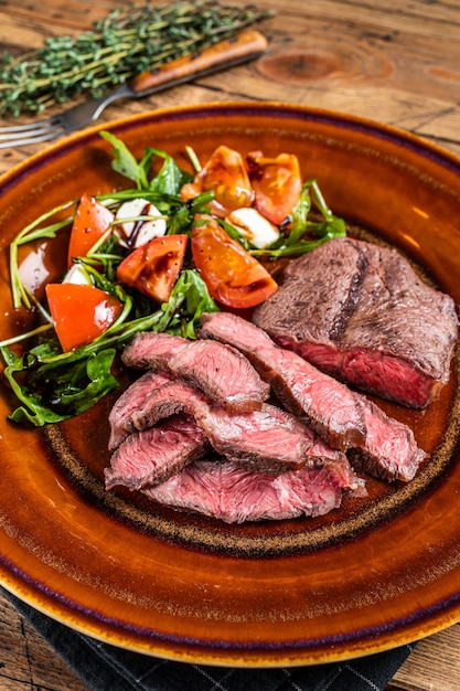 Lame supérieure d'huître rôtie au barbecue ou steak de viande de rosbif en fer plat sur une assiette avec salade.