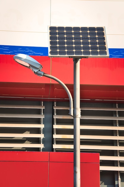 Un lampadaire alimenté par l'énergie solaire devant une façade de couleurs rouges et bleues intenses