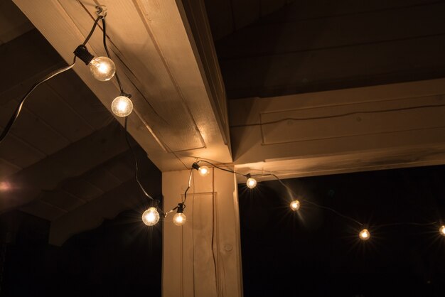 Lampadaires Décoratifs Accrochés à La Terrasse D'une Maison En Bois La Nuit. Lampes Décoratives Anciennes, éclairage Festif