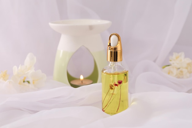 Lampe aromatique et huile essentielle de freesia sur un espace en tissu blanc pour le texte