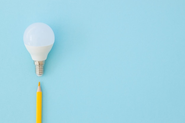 La lampe LED et le crayon se trouvent sur un fond bleu pastel