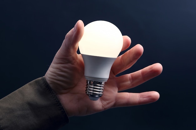 La lampe à LED moderne est tournée. Lumière LED incluse dans la paume d'une personne sur un mur sombre. industrie industrielle électrique