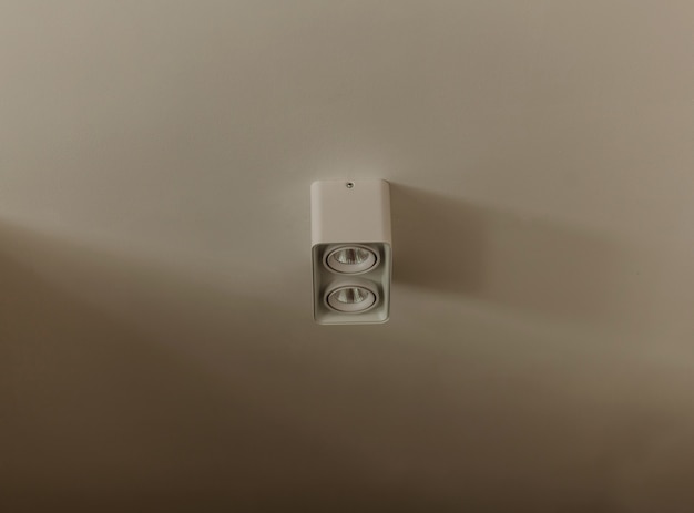 Lampe minimaliste accrochée au plafond blanc.