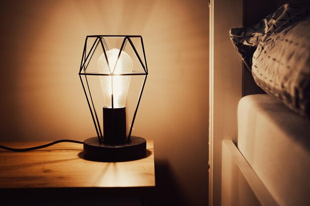 Lampe de nuit près du lit dans une chambre sombre