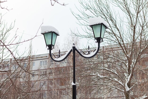 Lampe de rue dans le parc d'hiver. Immeuble en arrière-plan