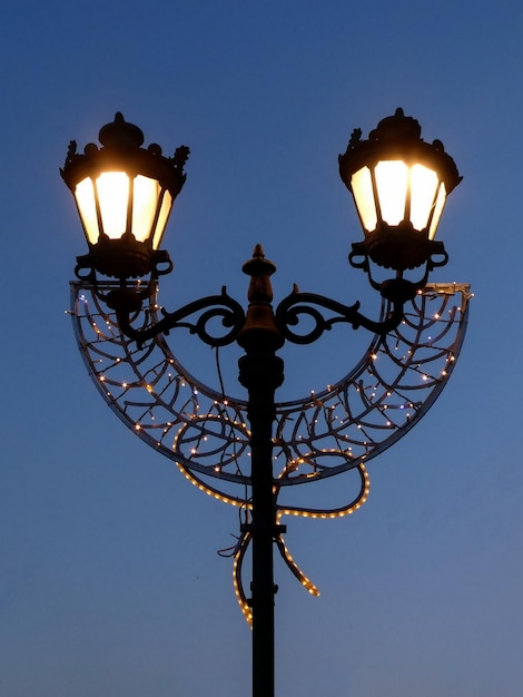 Lampe de rue avec décoration de Noël contre le ciel bleu