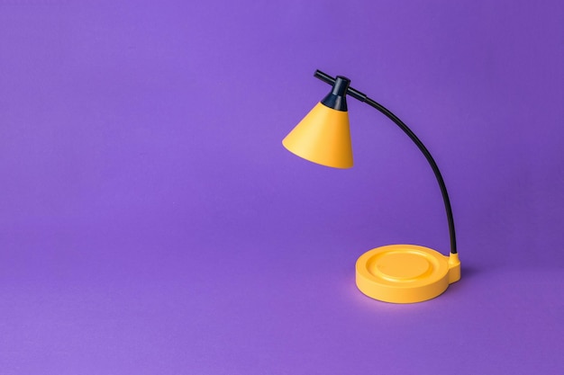 Une lampe de table jaune sur fond violet foncé