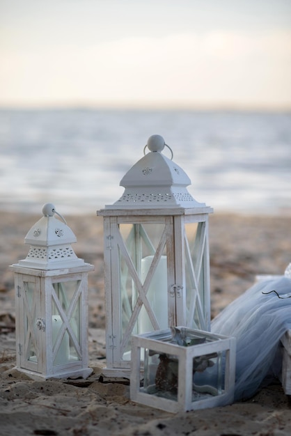 Photo lampes décoratives du soir avec des bougies sur la plage au coucher du soleil