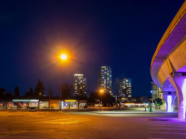 Landage urbain nocturne avec un train aérien et une lumière de rue lumineuse sur la place