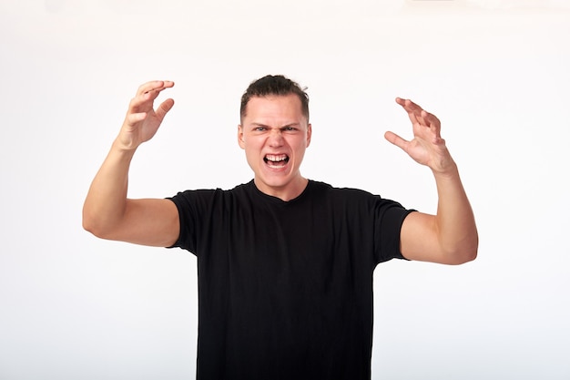 Le langage du corps. La domination des hommes. Jeune homme malheureux agressif en colère en chemise totale hurlant. Studio tourné sur fond blanc.