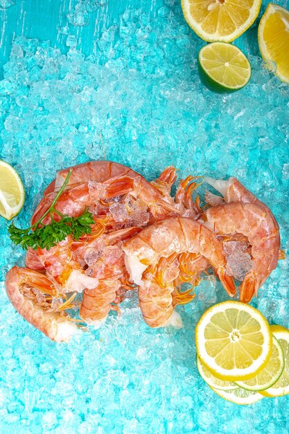 langoustines de crevettes fraîches rouges avec et sans tête, allongées sur le fond bleu glace de la mer, cerise