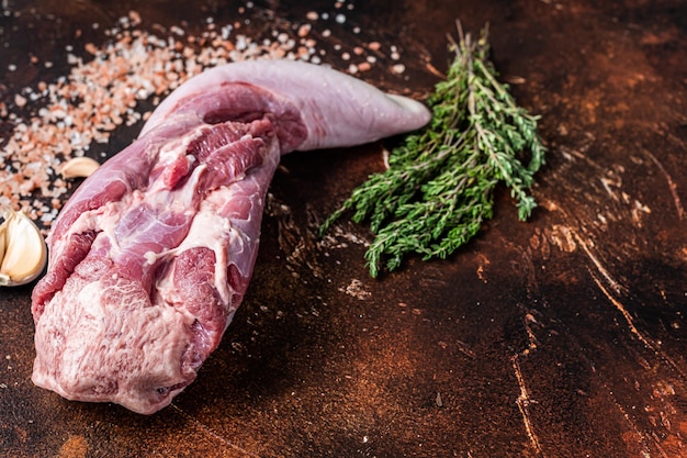 Langue de boeuf crue sur table de cuisine aux herbes. Fond sombre. Vue de dessus. Espace de copie.