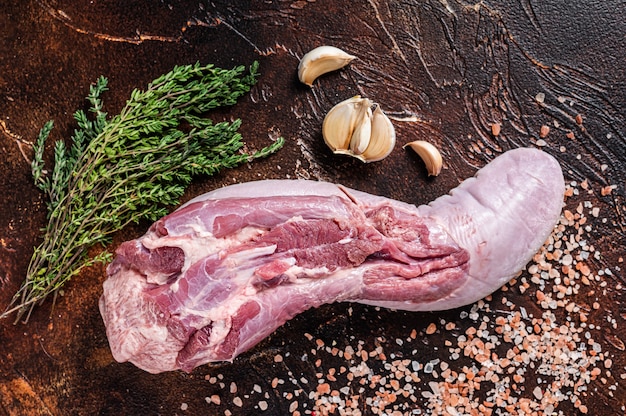 Langue de boeuf crue sur table de cuisine aux herbes. Fond sombre. Vue de dessus.