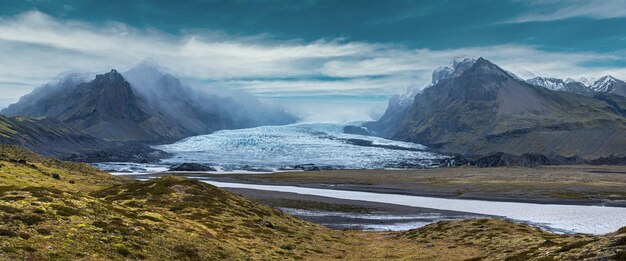 Photo la langue du glacier glisse de la calotte glaciaire du vatnajokull ou du glacier du vatna près du volcan sous-glaciaire oaefajokull islande lagune glaciaire avec blocs de glace et montagnes environnantes