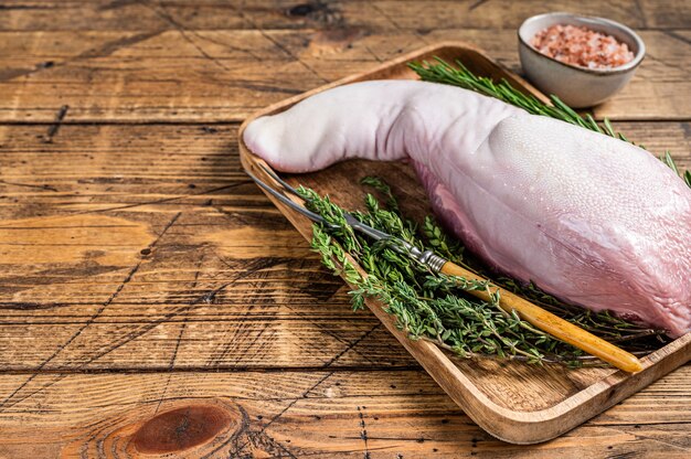 Langue de porc crue sur plateau de boucher avec couteau à viande. fond en bois. Vue de dessus. Espace de copie.