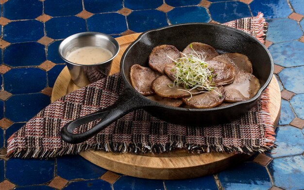 Langue de veau dans une poêle en fonte sur un support en bois