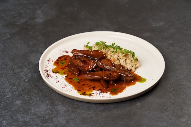 Langues d'agneau au four avec une bouillie de boulgour épicée dans une assiette blanche