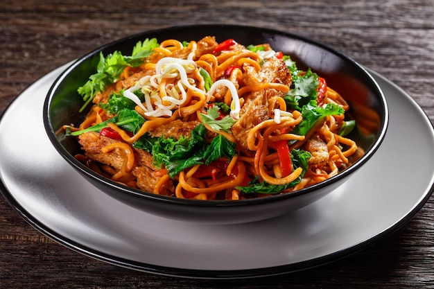 Lanières de viande de soja grillées avec des germes de soja aux nouilles aux œufs épicées coriandre et piment chou frisé dans un bol sur une table en bois cuisine asiatique