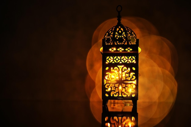 Lanterne arabe ornementale avec une bougie allumée qui brille la nuit
