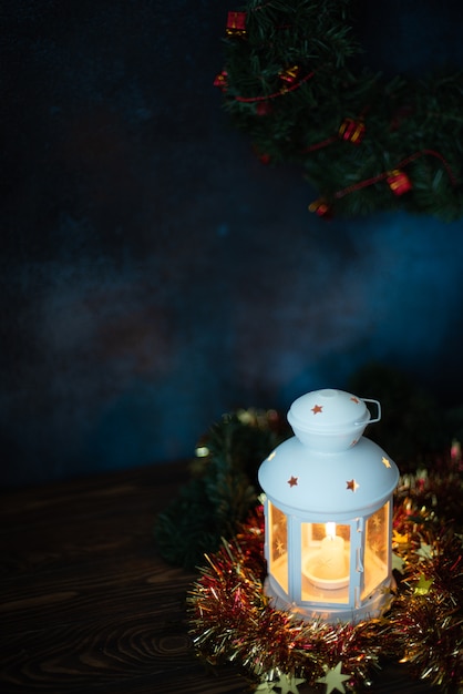 Lanterne blanche avec une bougie allumée et des branches de sapin