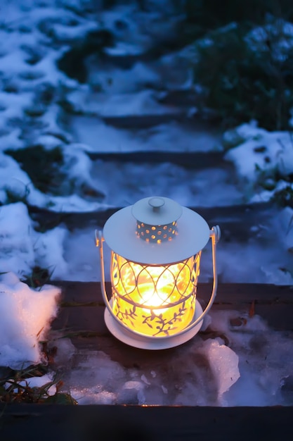 Lanterne décorative avec bougie allumée sur de vieux escaliers en bois dans le parc d'hiver le soir.