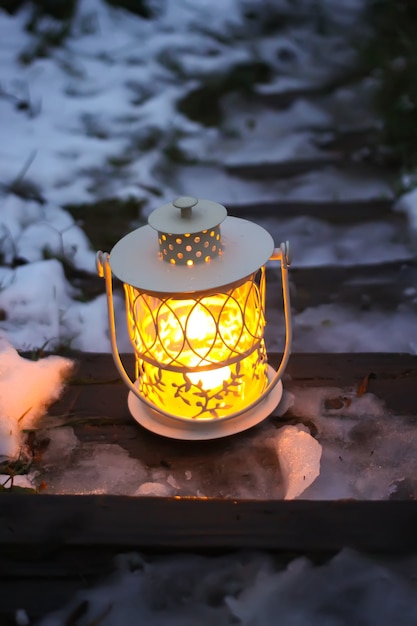 Lanterne décorative avec bougie allumée sur de vieux escaliers en bois dans le parc d'hiver le soir.