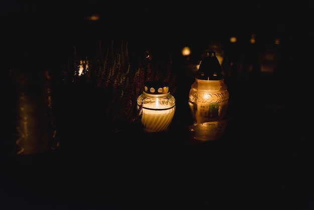 Lanterne de mémoire avec bougie allumée dans l'obscurité Bougies blanches allumées dans la nuit sombre avec lumières brillantes Focus sélectif