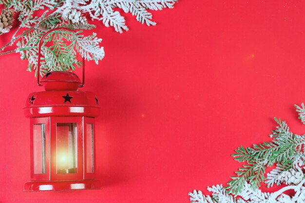 Lanterne de noël rouge et branches de noël dans la neige sur fond rouge, espace de copie
