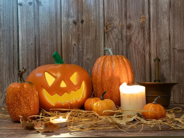 Lanterne à tête de citrouille d'Halloween avec des bougies et une citrouille sur fond de bois