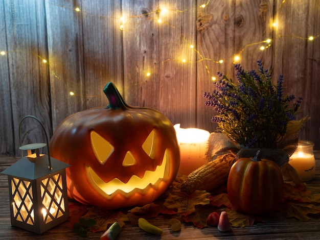 Lanterne à tête de citrouille d'Halloween avec des bougies et une citrouille sur fond de bois