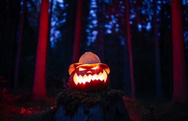 Lanterne traditionnelle à tête de jacks pour halloween sur fond de forêt rouge sombre concept d'hor...