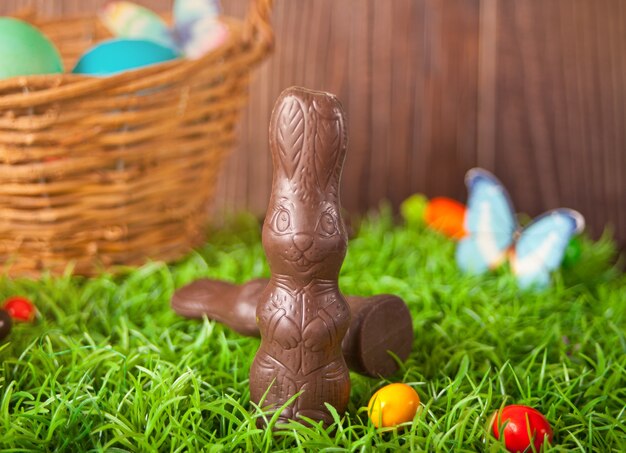 Lapin au chocolat de Pâques, bonbons de carottes dans l'herbe sur le fond en bois.