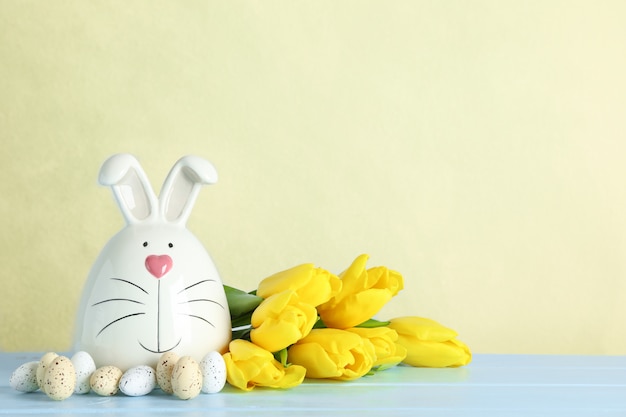 Lapin décoré et oeufs de Pâques sur table sur fond de couleur