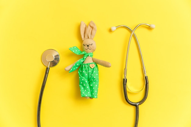 Lapin de jouet de conception tout simplement minimal et stéthoscope isolé sur fond jaune