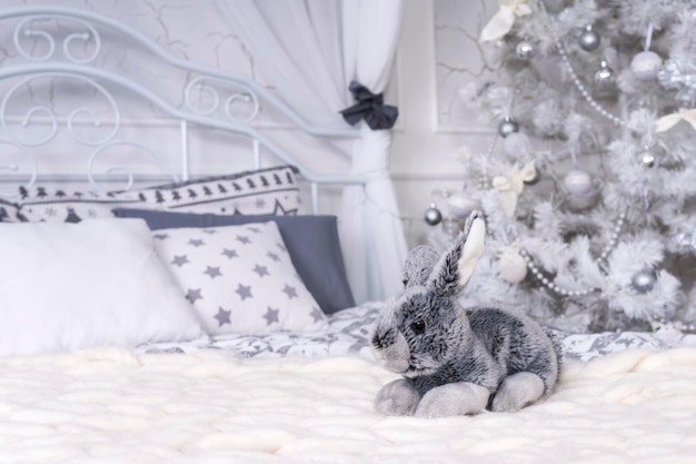 Lapin Jouet Dans Un Lit Sur Un Plaid Avec Un Arbre De Noël En Arrière-plan