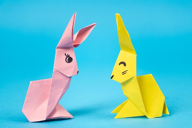 Un lapin en origami rose et jaune sur fond bleu