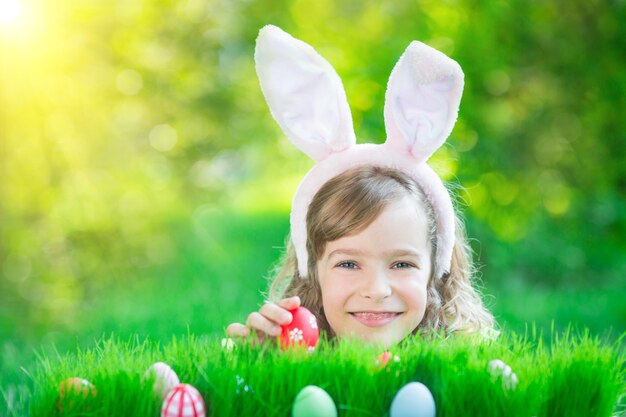 Lapin de Pâques. Enfant s'amusant en plein air. Enfant jouant avec des œufs sur l'herbe verte. Concept de vacances de printemps