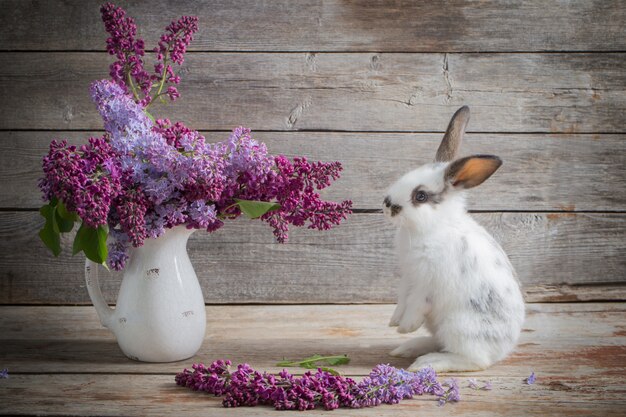 Photo lapin de pâques avec lilas sur un espace en bois