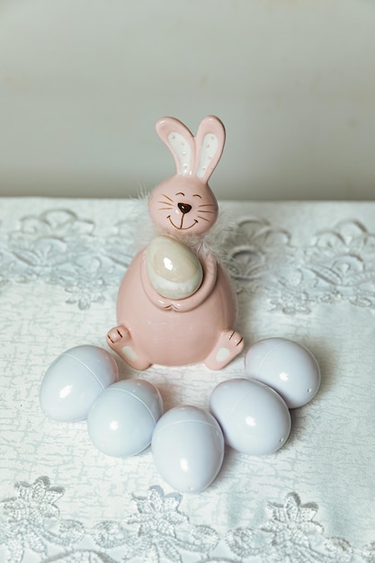 Un lapin de Pâques avec des œufs blancs sur une nappe blanche