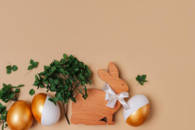 Lapin de Pâques et oeufs d'or avec des fleurs vertes sur fond beige Concept de vacances Joyeuses Pâques cardx9