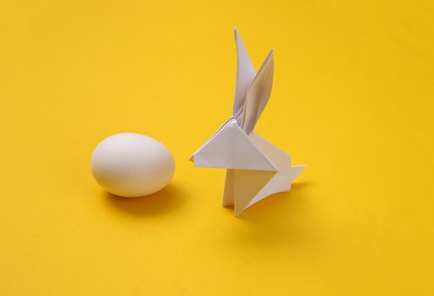 Lapin de Pâques en origami avec oeuf sur fond jaune