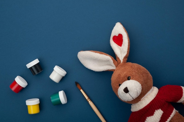 un lapin en peluche sur un fond bleu avec des peintures et un pinceau