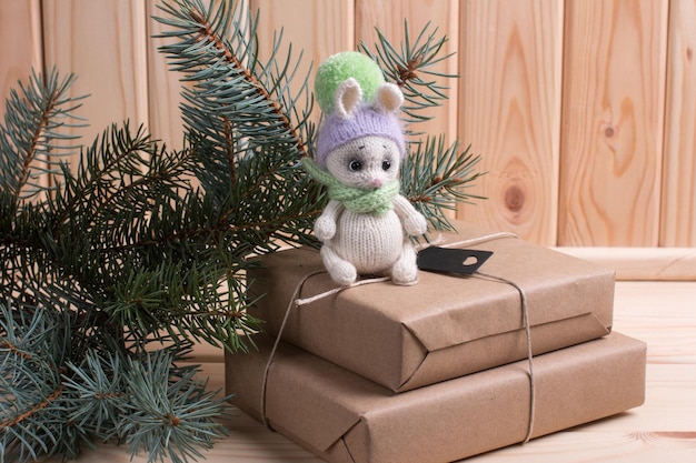 Lapin tricoté avec des cadeaux sur un fond en bois avec un sapin de Noël Nouvel An du lièvre 2023 fait à la main