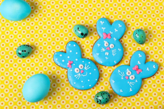 Lapins drôles de Pâques, biscuits de pain d'épice peints faits maison en glaçure sur une surface jaune, vue du dessus